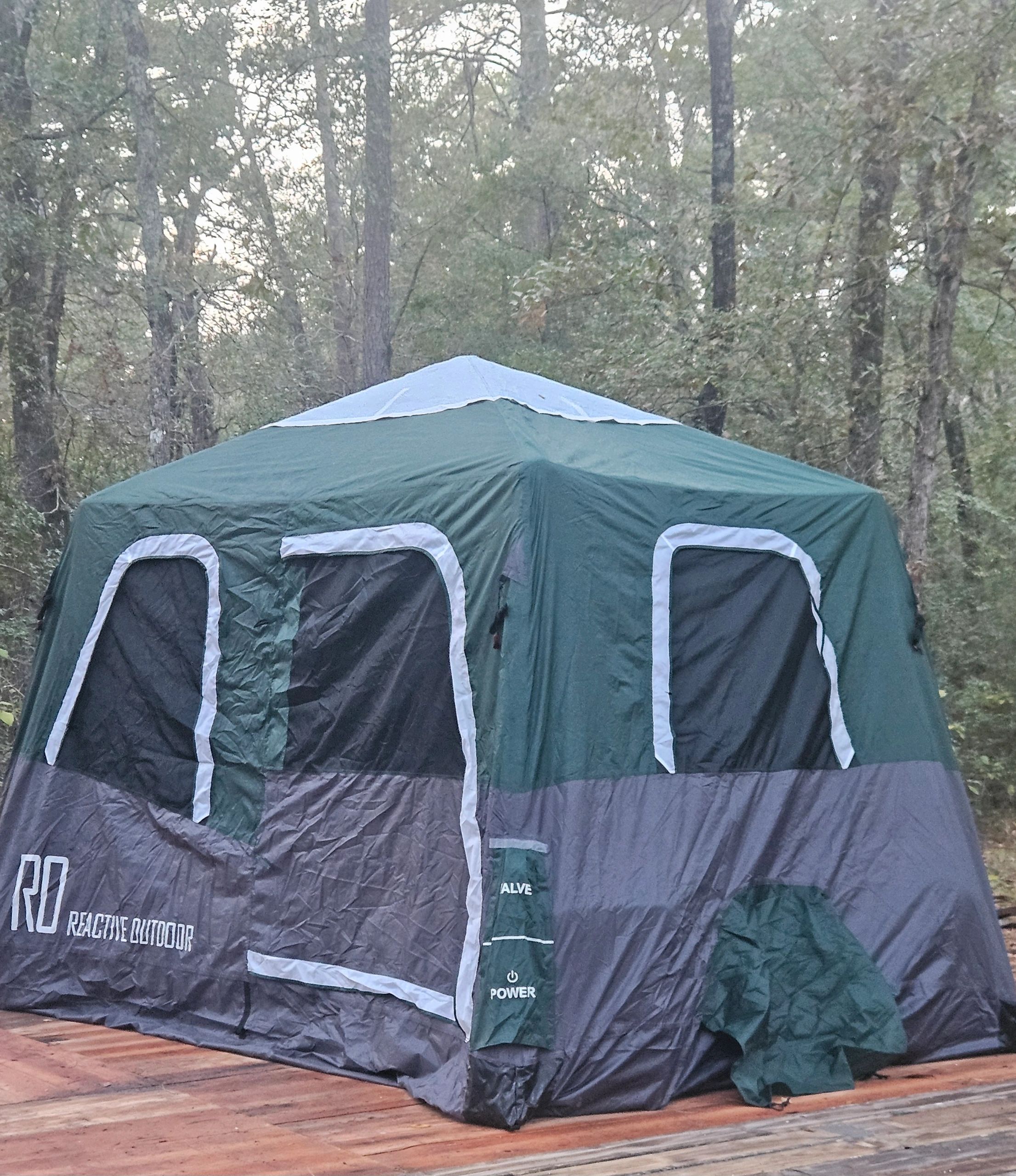 Large camping tent on wooden deck in forest